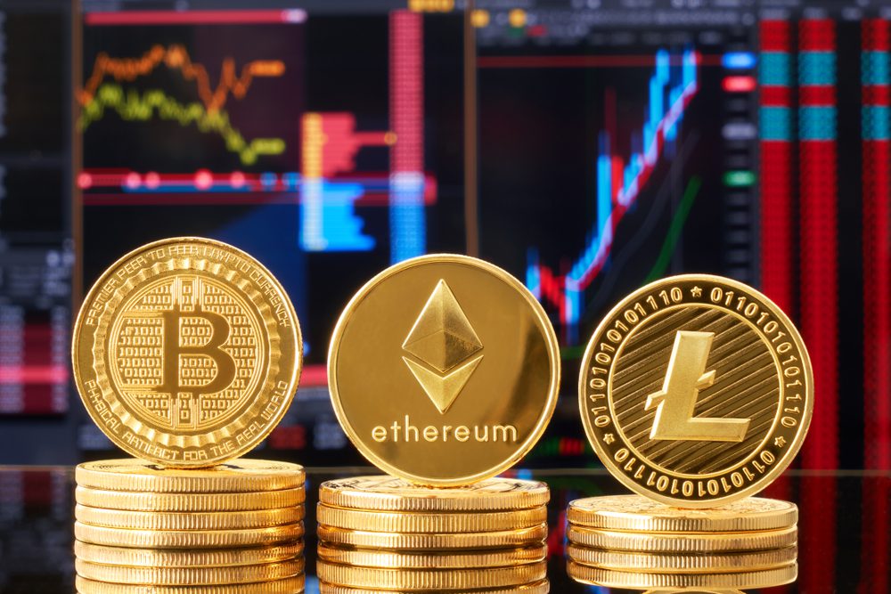 Tři zlaté mince kryptoměn (Bitcoin, Ethereum, Litecoin), na pozadí světlé finanční grafy