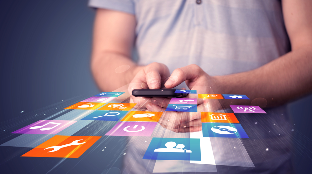Muž drží chytrý telefon s barevnými ikonami