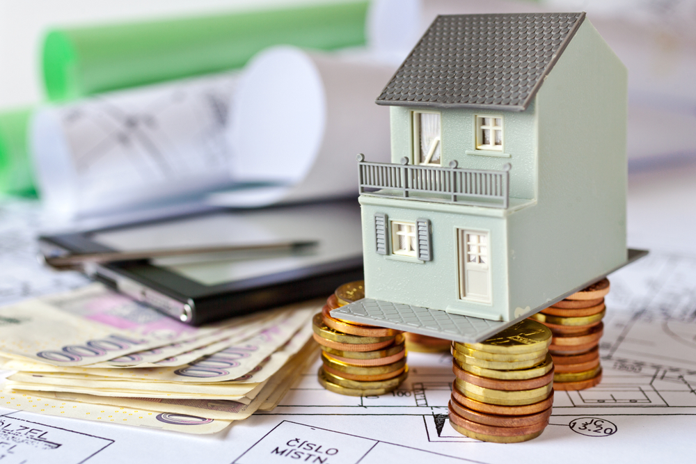 Ekonomika a finance, rodinný dům s českými mincemi, koncept hypotéky a splátek, rostousí zadlužení Česka