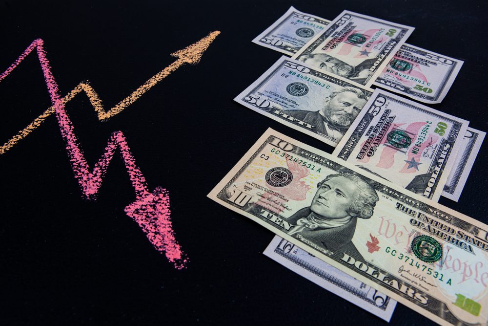 Koncept vývoje měnových kurzů amerických dolarů - čárový graf se šipkami směřujícími nahoru a dolů nakreslený křídou na tabuli