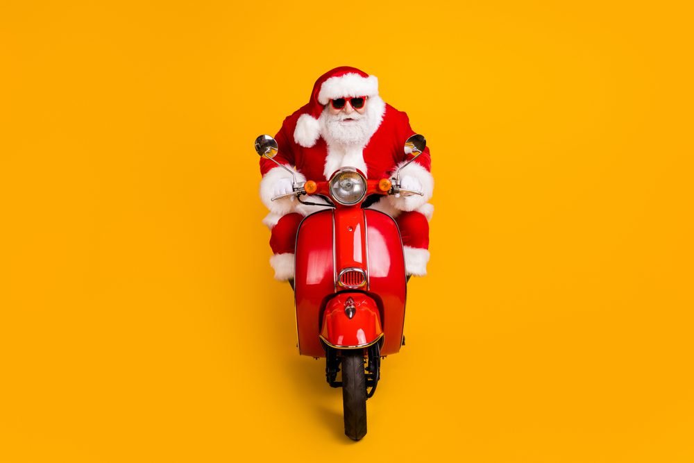 Santa Klaus se projíždí na motorce, žluto oranžové pozadí. Koncept Santa Klaus rally na akciových trzích